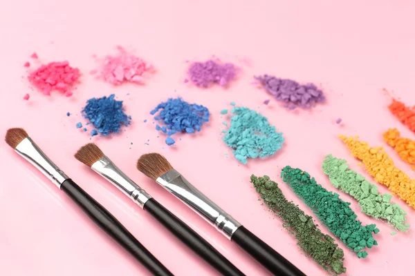 Arco iris triturado sombra de ojos y maquillaje profesional cepillo sobre fondo rosa —  Fotos de Stock