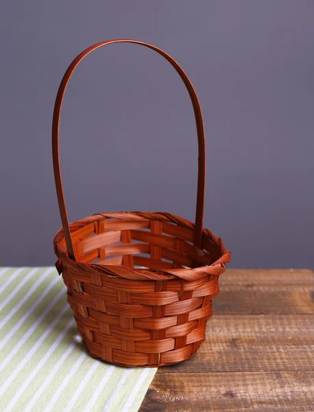 Empty wicker basket on wooden table, on dark background — Stock Photo, Image