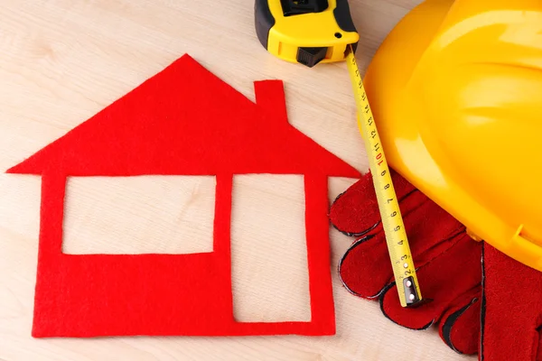 Casa de fieltro con casco y guantes sobre fondo de madera —  Fotos de Stock