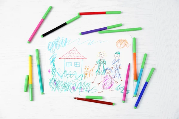 Kids drawing of family and colored pencils on wooden table — Stock Photo, Image