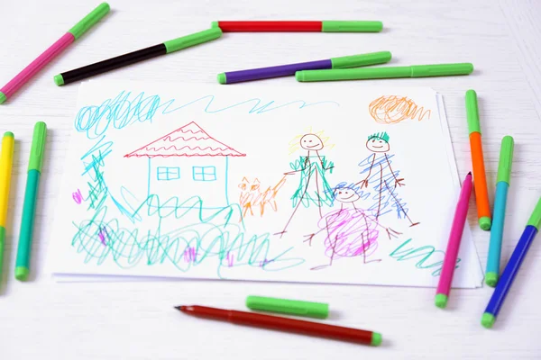 Barn ritning av familj och färgade pennor på träbord — Stockfoto