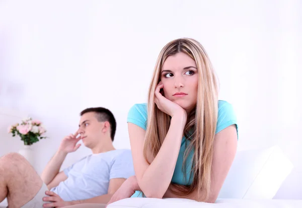 Young man and woman  conflict sitting on sofa argue unhappy, on home interior background — Stock Photo, Image