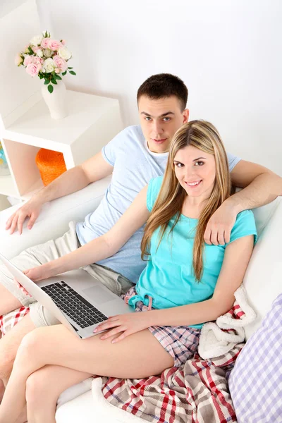 Kärleksfulla paret sitter med laptop på soffan, på hem inredning bakgrund — Stockfoto