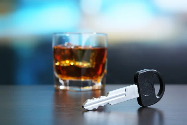 Composition with car key and glass of whiskey, on wooden table, on bright background — Stock Photo, Image