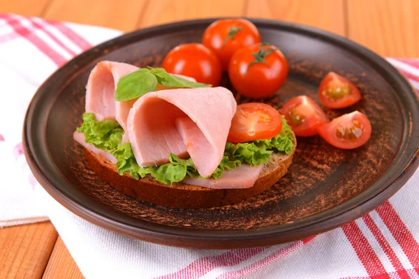 Lahodné sendviče se salátem a šunkou na talíři na stole zblízka — Stock fotografie