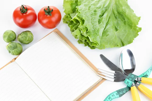 Talheres amarrados com fita métrica e livro com legumes isolados em branco — Fotografia de Stock