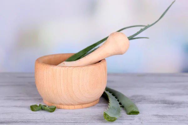 Hojas de aloe verde fresco en mortero de madera sobre mesa de madera —  Fotos de Stock