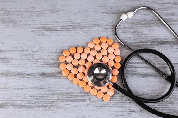Coeur de pilules et stéthoscope sur fond en bois — Photo
