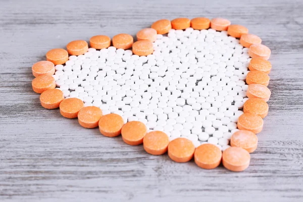 Heart of pills on wooden background — Stock Photo, Image