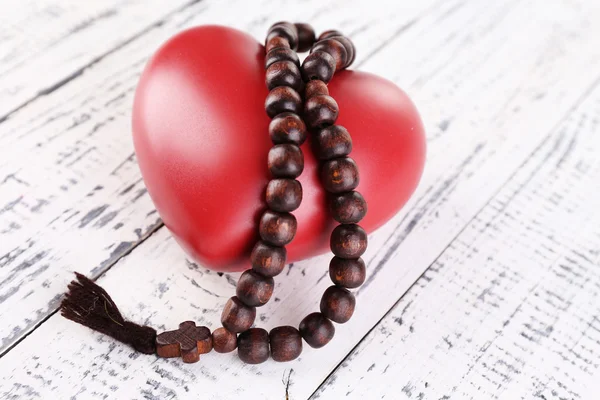 Heart with rosary beads on wooden background — Stock Photo, Image