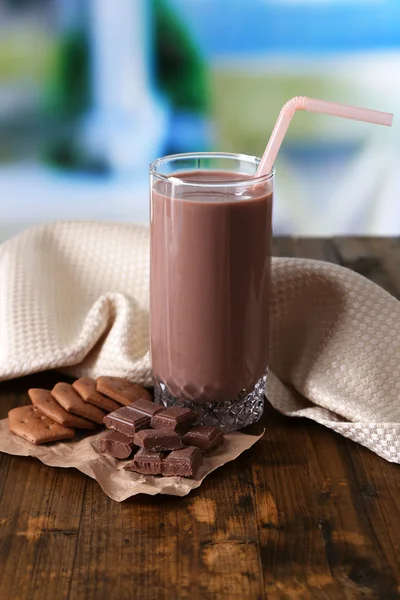 Leite de chocolate em vidro, na mesa de madeira, no fundo brilhante — Fotografia de Stock