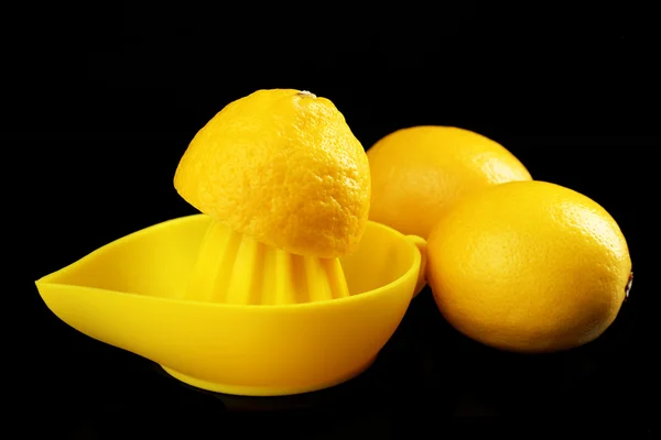 Citrus squeezer with lemons on black background — Stock Photo, Image