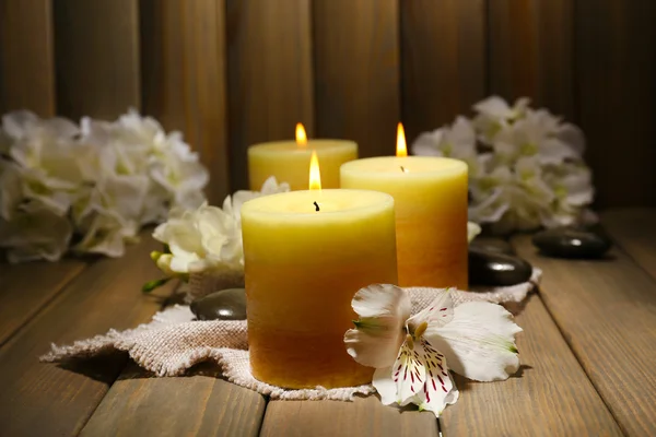 Hermosas velas con flores sobre fondo de madera — Foto de Stock