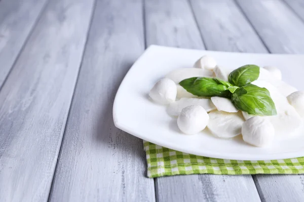 Tasty mozzarella cheese with basil on plate  on wooden background Stock Picture