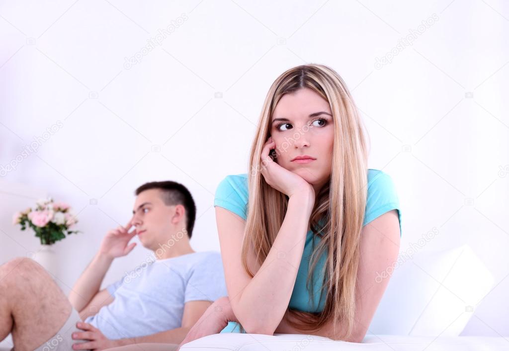 Young man and woman  conflict sitting on sofa argue unhappy, on home interior background