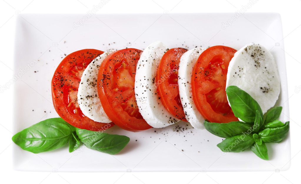 Caprese salad with mozarella cheese, tomatoes and basil on plate, isolated on white