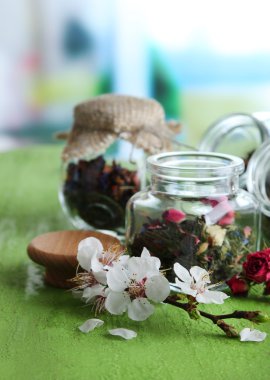 Parlak zemin üzerine ahşap masa üzerinde otlar ve çay cam kavanozlar 