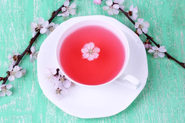 Voňavý čaj s kvetoucí větve na dřevěný stůl detail — Stock fotografie