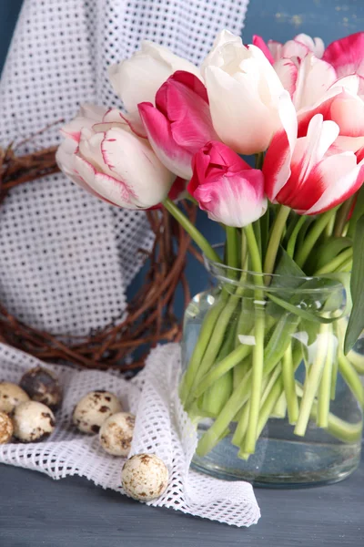 Composición con huevos de Pascua y hermosos tulipanes en jarra de vidrio sobre fondo de madera de color — Foto de Stock