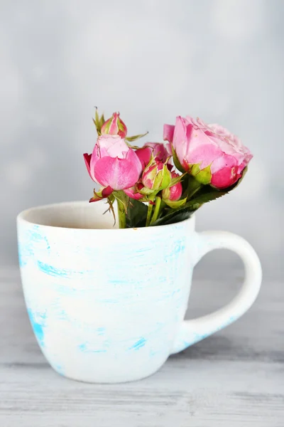 Schöne Rosen in Tasse auf hellem Hintergrund — Stockfoto