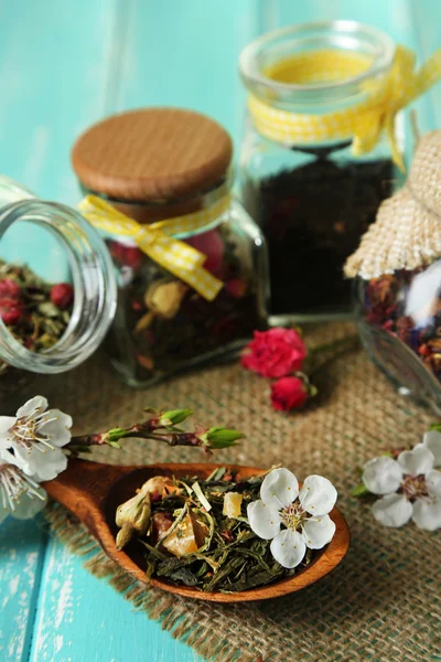 Assortment of herbs and tea in glass jars on wooden background — Stock Photo, Image