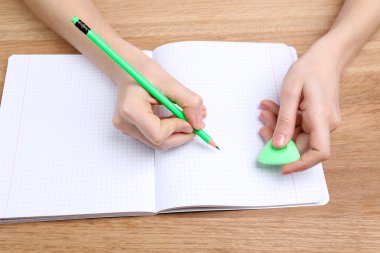 insan eli kalem kağıt ve erase kauçuk ahşap masa arka plan üzerinde yazma ile