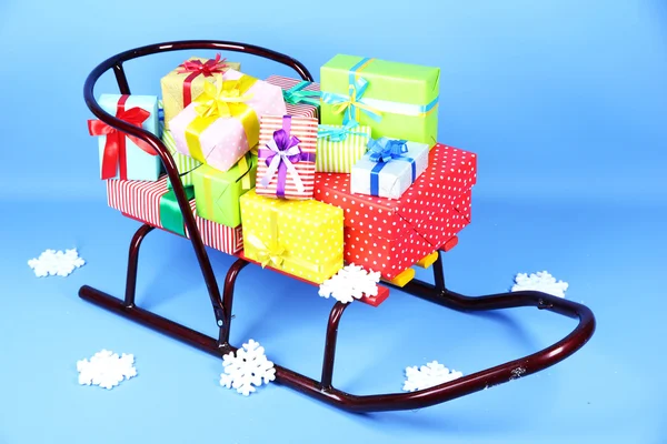 Schlitten mit Weihnachtsgeschenken, auf blauem Hintergrund — Stockfoto