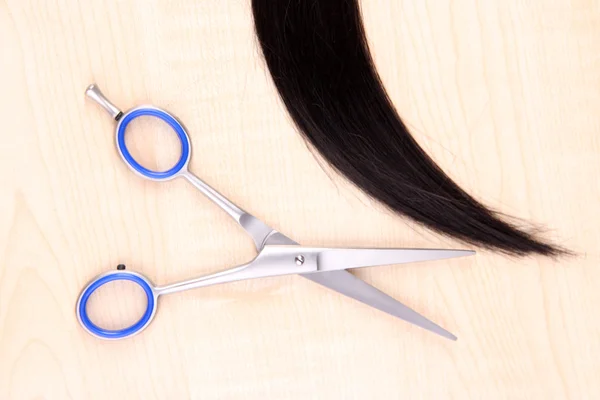 Cabello castaño largo y tijeras sobre fondo de madera —  Fotos de Stock