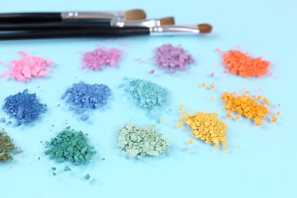 Regenboog verpletterd oogschaduw en professionele make-up borstel op blauwe achtergrond — Stockfoto