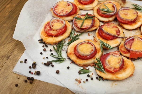 Małe pizze na papieru do pieczenia z bliska — Zdjęcie stockowe