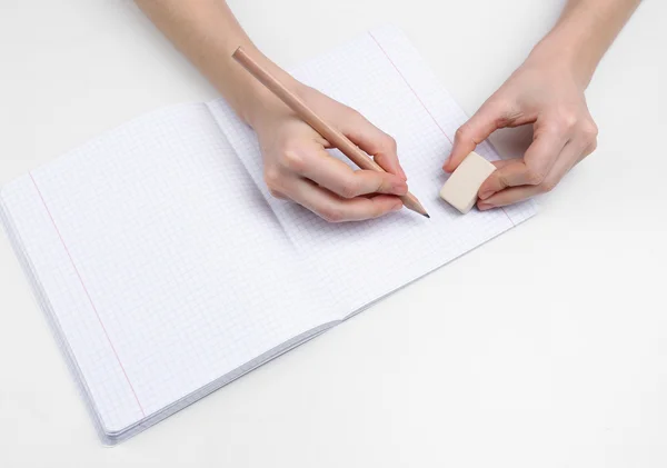 Human hands with pencil and erase rubber and notebook, isolated on white — Stock Photo, Image