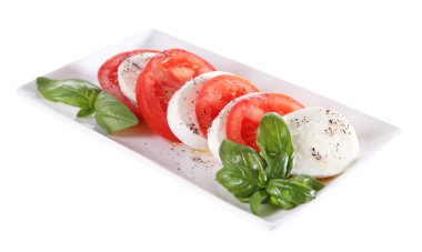 mozarella peyniri, domates ve fesleğen tabakta üzerine beyaz izole Caprese salatası