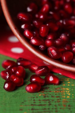 Olgun nar taneleri kase renkli ahşap zemin üzerinde