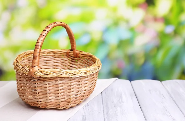 Panier en osier vide sur table en bois, sur fond lumineux — Photo