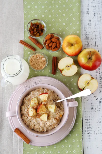 Tasty oatmeal with apples and cinnamon on table close up — Stock Photo, Image