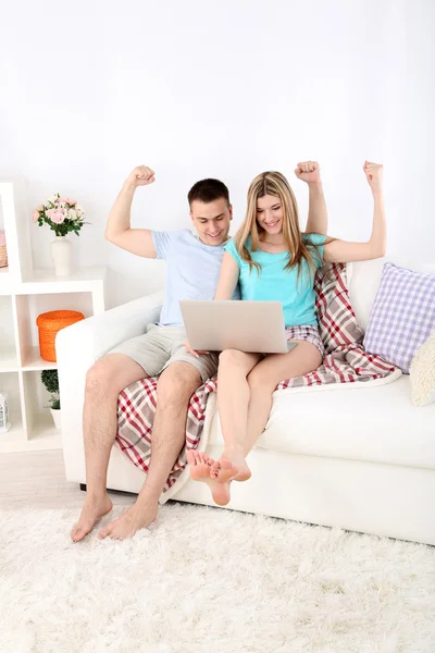Verliefde paar zitten met laptop op de Bank, op huis interieur achtergrond — Stockfoto