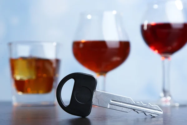Σύνθεση με αυτοκίνητο κλειδί και ποτήρια ποτό, στο ξύλινο τραπέζι, σε φωτεινό φόντο — Φωτογραφία Αρχείου