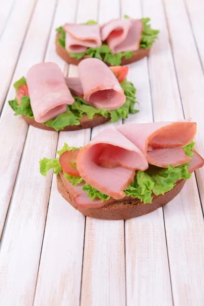 Läckra smörgåsar med sallad och skinka på bordet närbild — Stockfoto