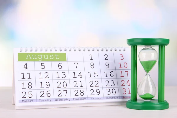 Hourglass and calendar on bright background — Stock Photo, Image