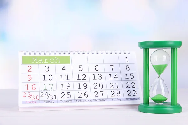 Hourglass and calendar on bright background — Stock Photo, Image