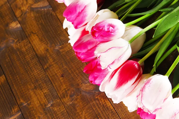 Schöne Tulpen auf farbigem Holzhintergrund — Stockfoto