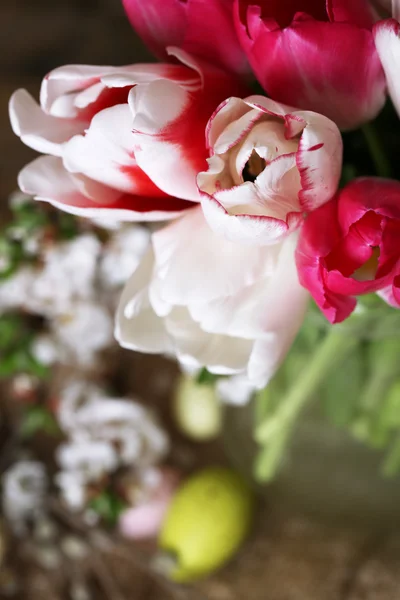 Složení s velikonoční vajíčka a krásné tulipány ve skleněné konvici na dřevěné pozadí — Stock fotografie