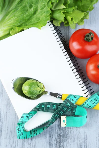 Anteckningsboken med mätning av tejp och grönsaker på trä bakgrund — Stockfoto