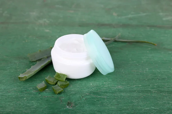 Crème et feuilles d'aloès vert frais sur table en bois — Photo