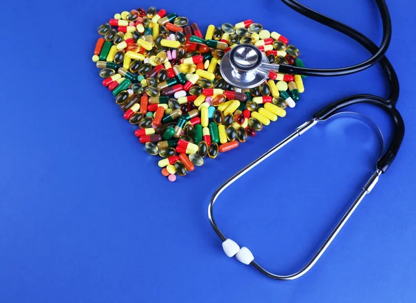Heart of pills and stethoscope on blue background — Stock Photo, Image
