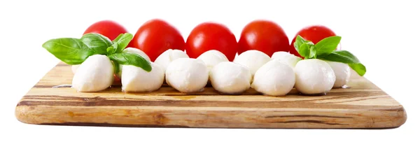 Tasty mozzarella cheese balls with basil and red tomatoes, on cutting board, isolated on white — Stock Photo, Image