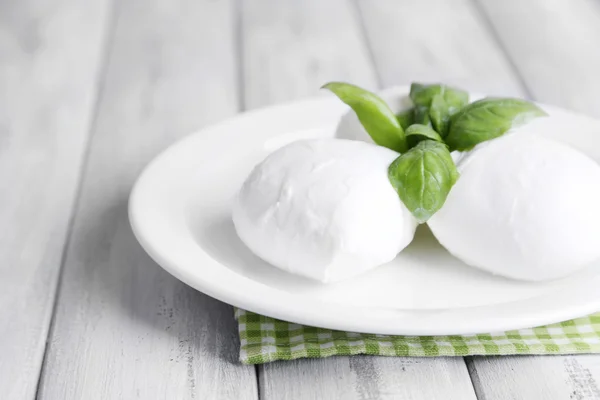 Gustosa mozzarella con basilico su piatto su fondo di legno — Foto Stock