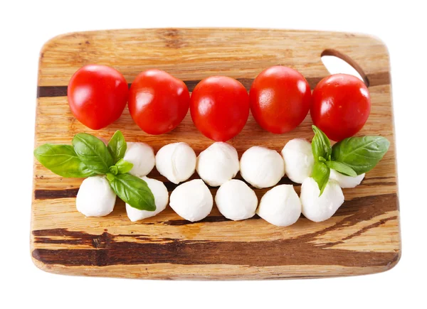 Sabrosas bolitas de queso mozzarella con albahaca y tomates rojos, sobre tabla de cortar, aisladas sobre blanco — Foto de Stock