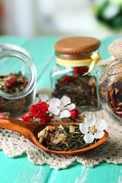 Assortiment van kruiden en thee in glazen potten op houten tafel, op lichte achtergrond — Stockfoto
