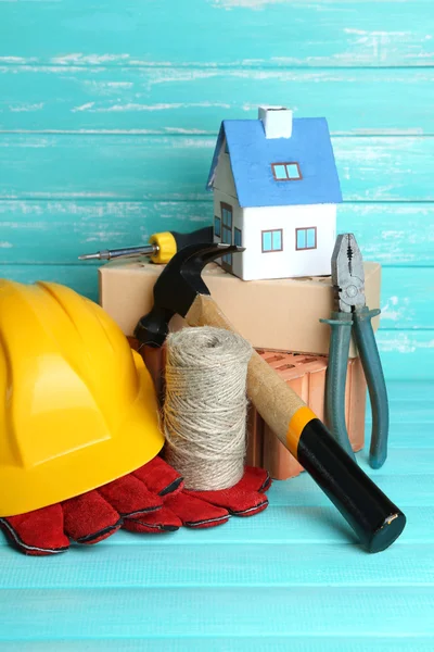 Composition with safety helmet, leather gloves, tools and decorative house on wooden background — Stock Photo, Image